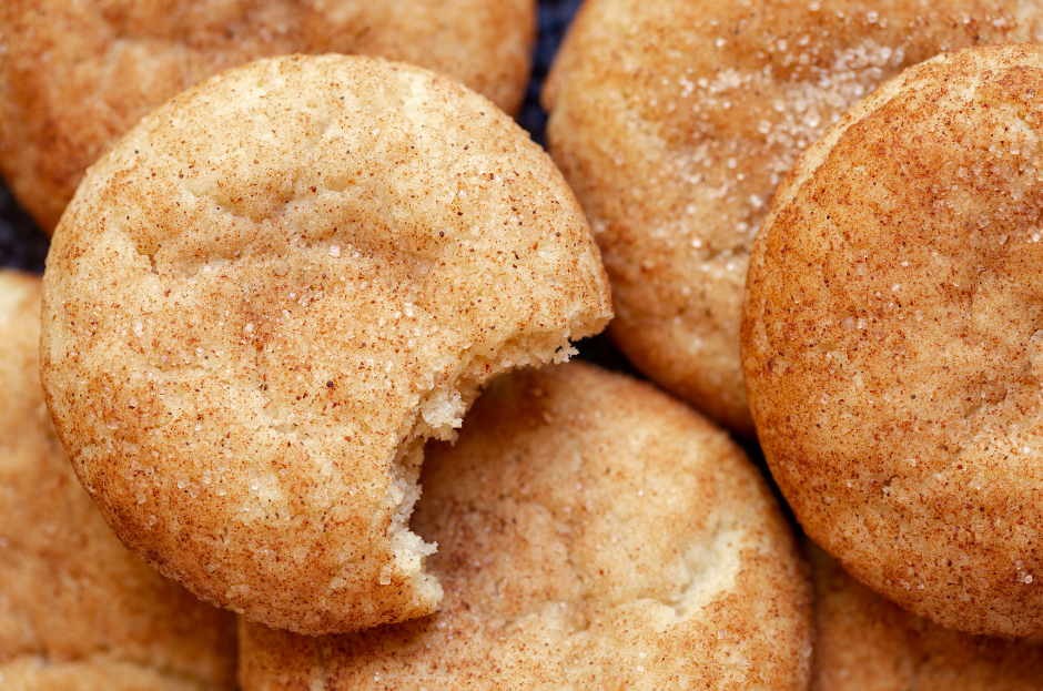 Image of a pile of snickerdoodles, with a bite out of the one on top