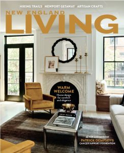 New England Living magazine cover showcasing a modern living room with a white mantelpiece, black framed mirror, artwork, and a mustard-colored armchair. The cover promotes articles about hiking trails, Newport, artisan crafts, home design, Gray Malin, and Patrick Dempsey's cancer support foundation.